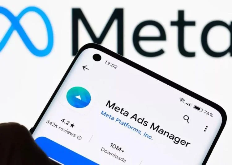 Aplikasi Meta Ads Manager di smartphone dengan logo Meta di latar belakang